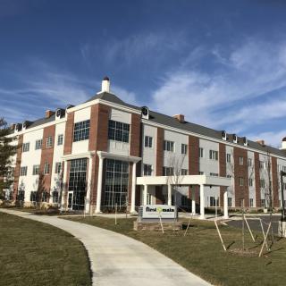 A modern multi-story building with brick and white facade under a clear blue sky.