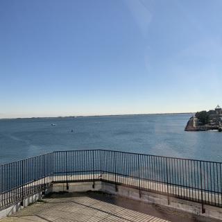 A clear view of the ocean with blue skies and a coastal railing.