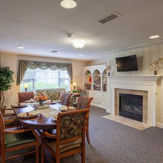 A cozy living room with a dining area, featuring a fireplace and a wall-mounted television.