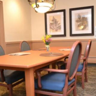 A meeting room with a wooden conference table, surrounded by chairs, adorned with wall art and a central lighting fixture.