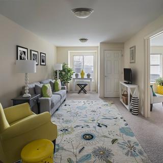A cozy living room with modern decor featuring a sofa, armchair, TV stand, and decorative plants.