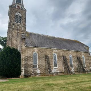 An old stone church standing proudly against a cloudy sky.