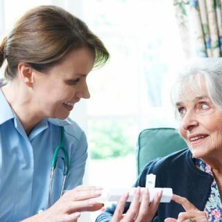 A nurse assisting an elderly woman with her medication in a home setting.