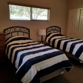 A cozy bedroom with twin beds featuring blue and white striped bedding.