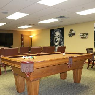 A cozy recreation room featuring a pool table, comfortable seating, and artwork on the walls.
