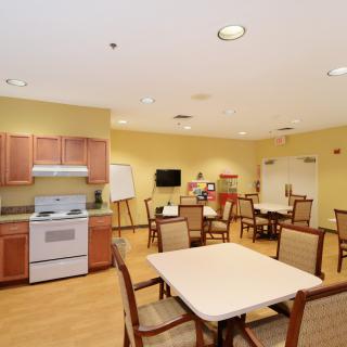 A communal kitchen and dining area with tables, chairs, and appliances.