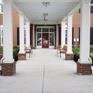 Entrance of a building with columns, benches, and a red door.
