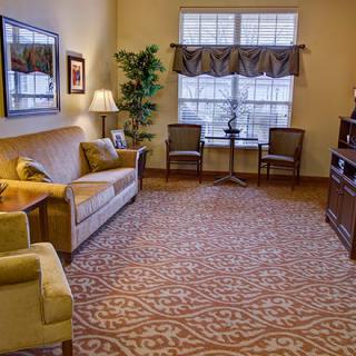 A cozy living room with a sofa, armchairs, and a carpeted floor.