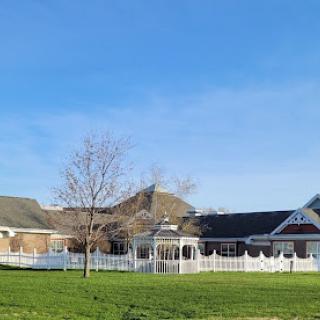 A picturesque view of a residential building with a white fence under a clear blue sky.