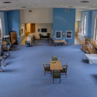 A spacious room with blue walls, multiple tables and chairs arranged in an open layout.