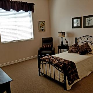 A cozy bedroom with a single bed, decorated with warm colors and artistic elements.