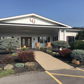 A well-maintained building entrance with a landscaped garden and a paved pathway leading to the doors.