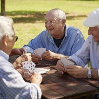 A group of elderly friends enjoying a game of cards outside in a park.