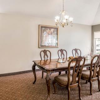 A traditional dining room with a wooden table and chairs, a chandelier above, and artwork on the wall.
