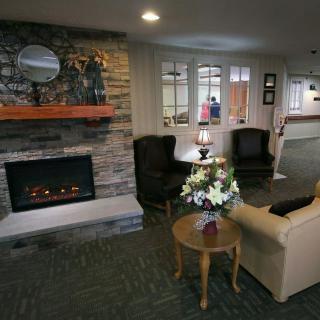 A cozy living room interior with a stone fireplace, armchairs, and a floral centerpiece on a wooden table.