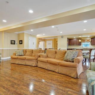 Spacious living room with cozy sofas and hardwood flooring leading into an open kitchen area.