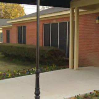 A brick building with large windows and a sidewalk in front.