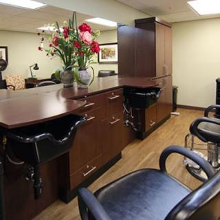 A well-organized hair salon interior with chairs, desks, and decorative flowers.