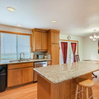 A modern kitchen with wood cabinets and a granite countertop island, showcasing open space and ample natural light.