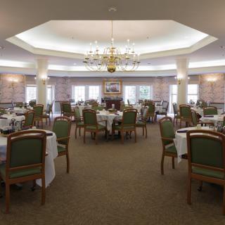 An elegant dining room with neatly arranged tables and a chandelier.