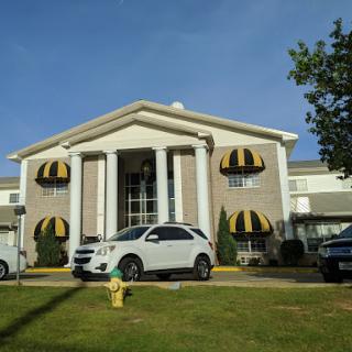 A stylish hotel featuring classic architecture and yellow awnings, with cars parked out front.