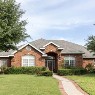 A suburban brick house with a well-maintained front yard.