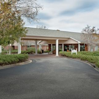 A building entrance with a circular driveway surrounded by greenery.