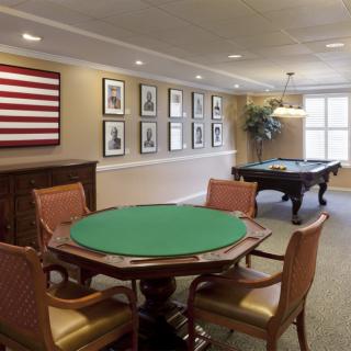 A well-appointed game room featuring a poker table and billiard table, adorned with framed pictures and an American flag.