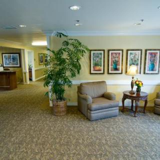 A cozy lobby area featuring comfortable chairs, a potted plant, and framed artwork on the wall.