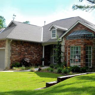 A suburban brick house with a well-maintained lawn and landscaping.