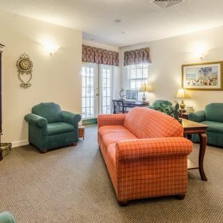 A cozy living room with an orange sofa, green armchairs, and tasteful decor.