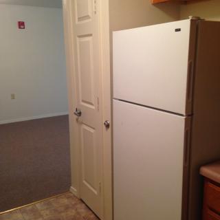 A small kitchen area featuring a refrigerator and adjacent door.