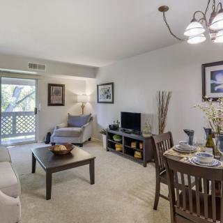 A cozy living room with an adjacent dining area featuring comfortable seating and a television.