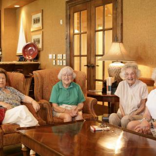 A group of elderly women sitting together in a living room.