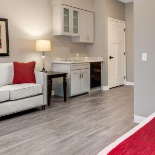 A modern living room with a white sofa, red accents, and hardwood flooring.