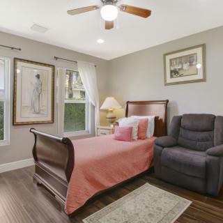 A cozy bedroom with a single bed, armchair, and decorative art on the walls.