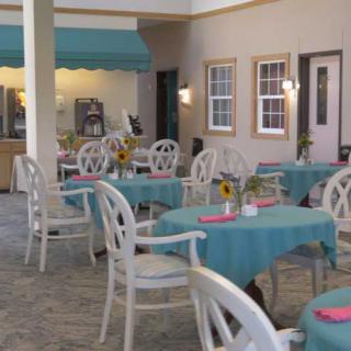 A charming outdoor restaurant patio with tables adorned with teal tablecloths and sunflowers.
