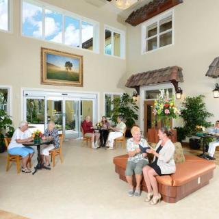 A bright and spacious lobby with people socializing in a comfortable seating area, surrounded by plants and artwork.