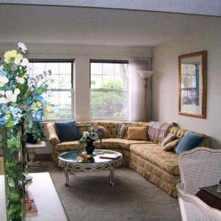 A cozy living room with a sectional sofa and coffee table near large windows.