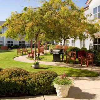 A well-maintained garden courtyard with trees, benches, and a winding pathway.
