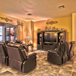 A well-furnished living room with leather chairs and an entertainment center.