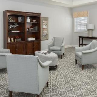 A cozy living room with upholstered armchairs, a wooden bookshelf, and a patterned carpet.