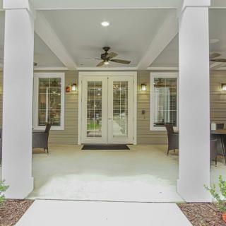A welcoming porch area with columns, featuring a ceiling fan and patio furniture.