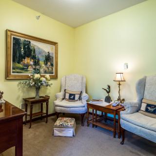 A cozy living room with comfortable chairs, a decorative painting on the wall, and soft lighting.