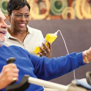 A healthcare professional assists an elderly man during a therapy session.