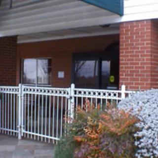 A building entrance with a white fence and plants in the foreground.