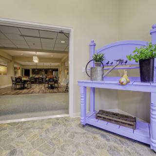 A purple shelf with plants decorates the entrance to a dining area.