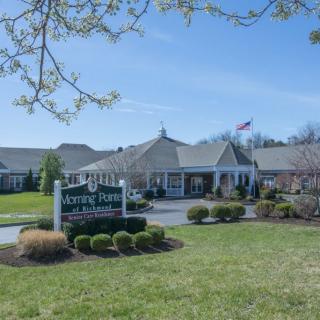 A scenic view of a building with a prominent sign on a sunny day, surrounded by well-maintained lawns and trees.