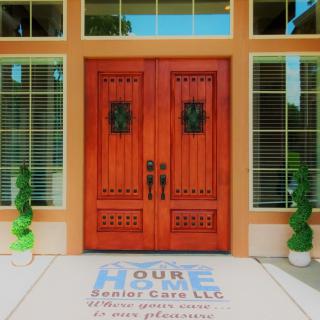A welcoming double wooden front door flanked by large windows and decorative plants.