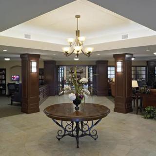 A spacious and elegant lobby with a central table, chandelier lighting, and tasteful decor.